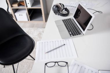 Kağıt ve dizüstü bilgisayar masasında topografyanın kulaklık ile ilgili notlar