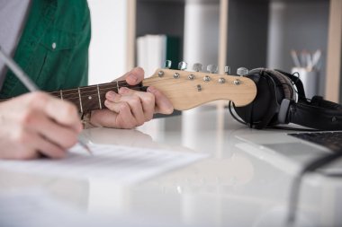 Erkek gitarist notlar çizerken dizeleri dokunmadan