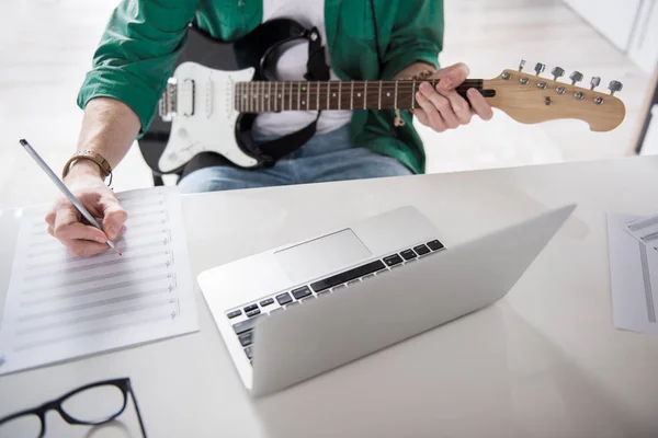 Male hands writing melody for guitar performance