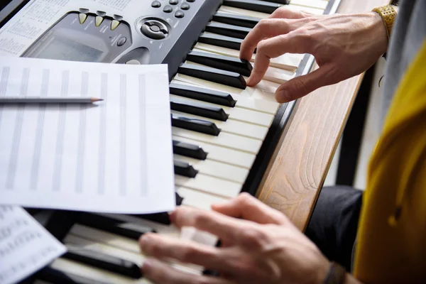 Male arms touching keys of electric piano