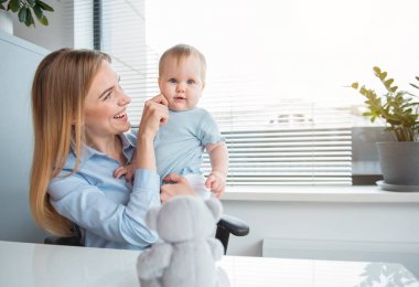 Gülen bebek anne kollarda oturma