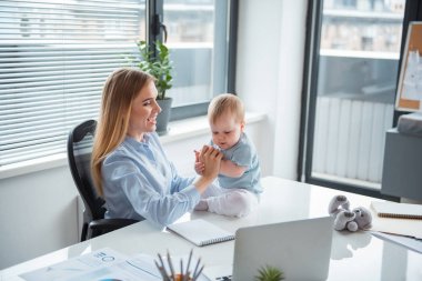 Neşeli kız ve ofiste oynayan bebek