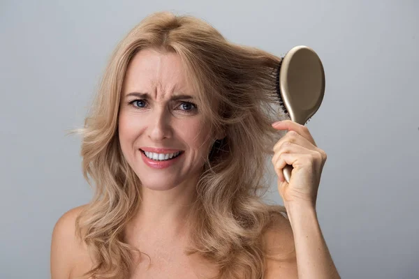 Disappointed female is holding hairbrush and expressing annoyance — Stock Photo, Image