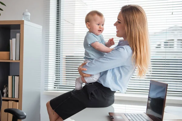 Beaming mother holding cheerful baby on arms — Stock Photo, Image