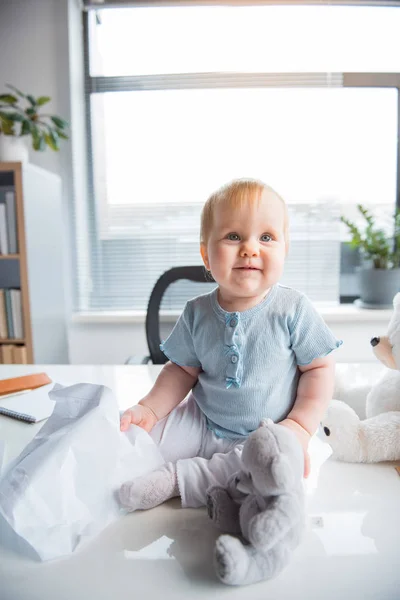 Zářící malé dítě sedí na stole — Stock fotografie