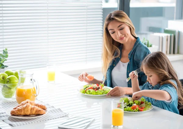 Happy parent and child eating salad with joy — Stock Photo, Image