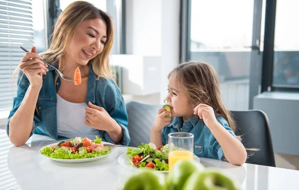 Glad mom feeding her kid by salad — Stock Photo, Image