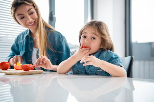 Веселый ребенок пробует здоровую пищу на кухне — стоковое фото