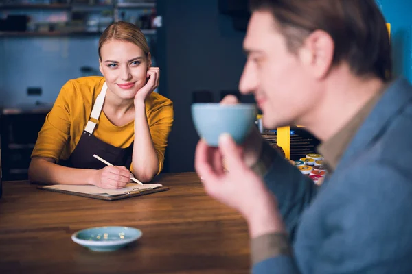 Uitgaande werknemer kijken naar bezoeker in café — Stockfoto