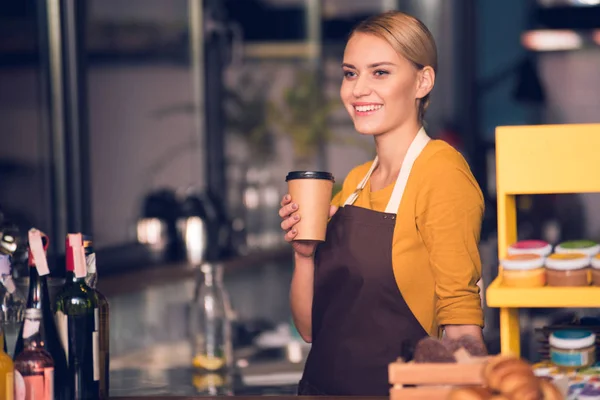 Utadvendt kvinne som smaker drikke på jobben – stockfoto