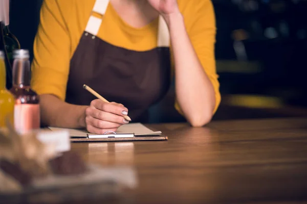 Woman arm noting on clipboard in cafe — Stock Photo, Image