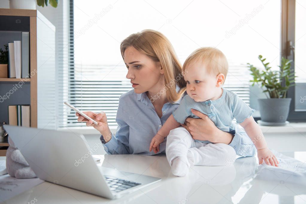 Serious mom working at office with baby