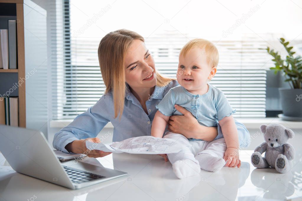 Happy businesswoman working and taking care of baby