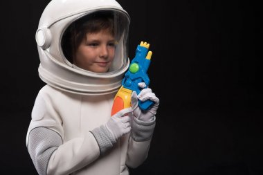 Pleasant kid cosmonaut is playing with toy gun clipart