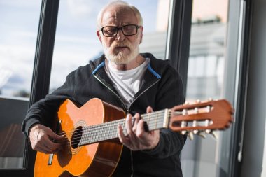 Sakin yaşlı adam evde gitar çalmak