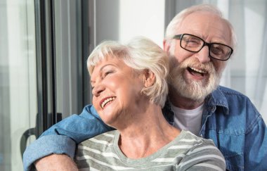 Gülümseyen yaşlı adam ve kadın kucaklayan