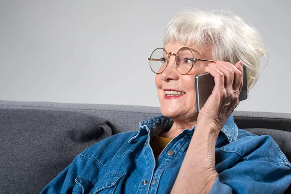 Віддана чудова дама розмовляє по телефону сидячи на дивані — стокове фото