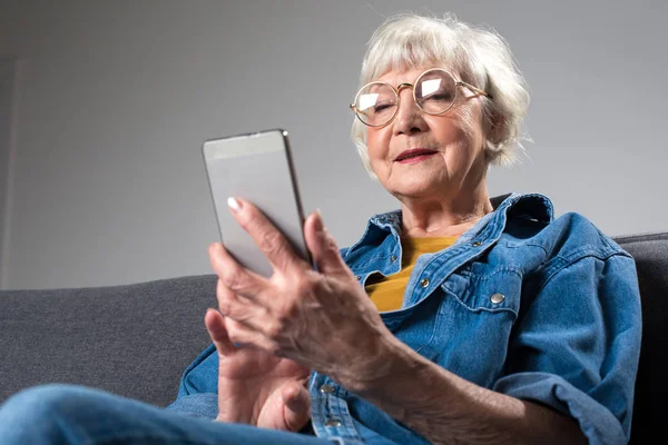 Розумна літня концентрована жінка тримає мобільний телефон — стокове фото