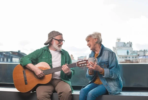 Amorous senior couple relaxing with guitar and tea
