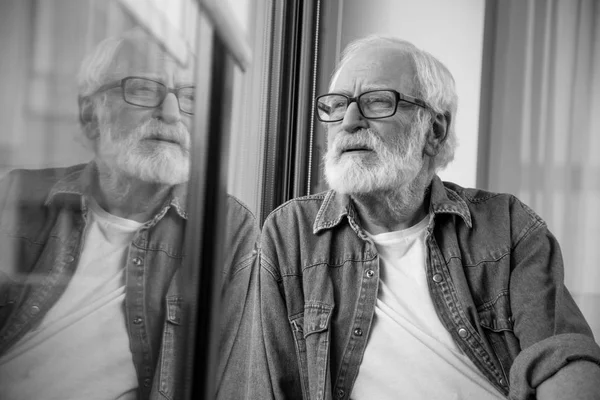 Pensionista triste pensativo mirando a la distancia mientras está sentado en casa — Foto de Stock