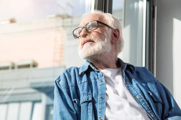 Vecchio sognante seduto a casa e godendo di tempo soleggiato — Foto Stock