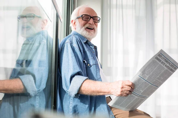 Laughing bearded old pensioner holding magazine — Stock Photo, Image