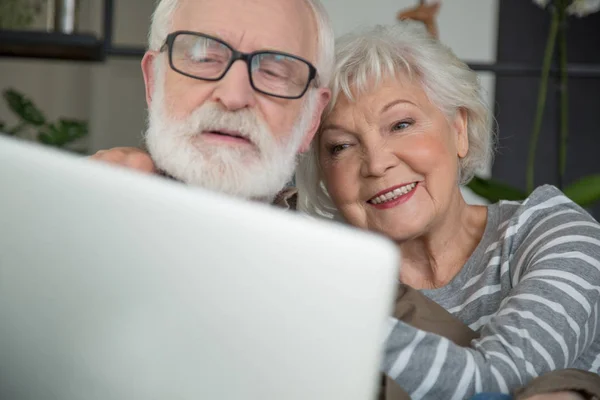 Feliz pareja de ancianos mirando en el cuaderno en casa — Foto de Stock