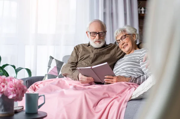 Sinceros pensionistas encantadores descansando en casa con libro — Foto de Stock