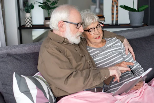 Curiosa pareja de ancianos discutiendo memoria encantadora sentado en el sofá — Foto de Stock