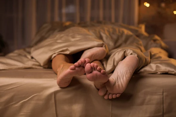 Pernas de homem afetuoso e mulher que se deleitam em camas — Fotografia de Stock