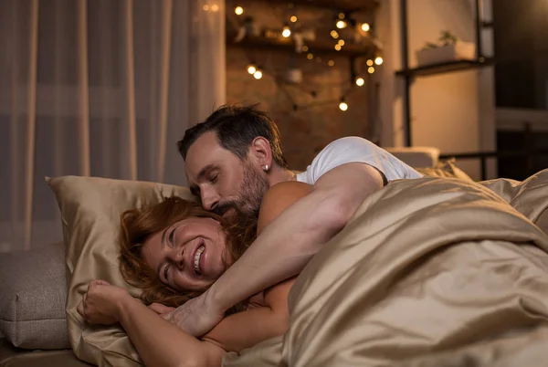 Glad man och hustru avkopplande i sängkläder — Stockfoto