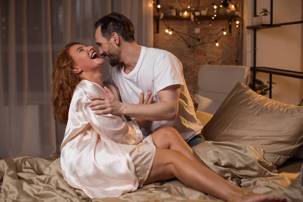 Hombre y mujer sonrientes sentados en la cama — Foto de Stock