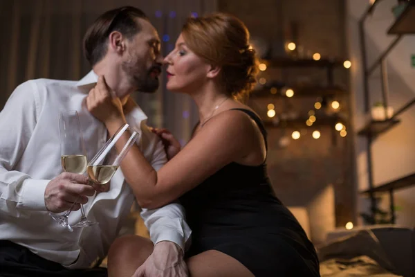 Hombre y mujer imapasionados bebiendo champán en la cama — Foto de Stock