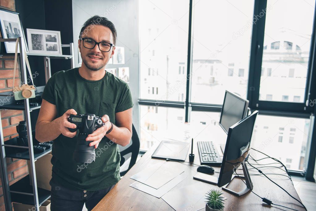 Cheerful male keeping camera in hands