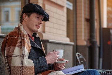 Genç adam kahve ve günlüğü ile rahatlatıcı dalgın