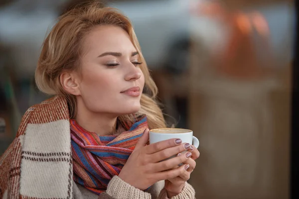 Chica encantadora oliendo aroma de café mientras está sentado al aire libre — Foto de Stock