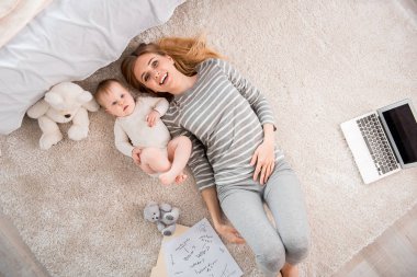 Neşeli anne ve sakin bebek halı üzerinde rahatlatıcı