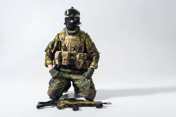 Soldado sério situado perto do rifle de assalto — Fotografia de Stock