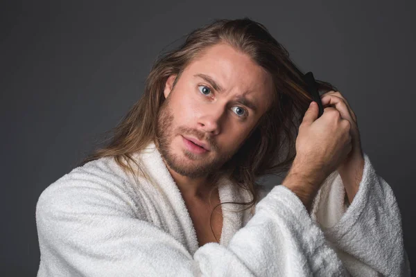 Hombre enfocado peinando el pelo largo — Foto de Stock