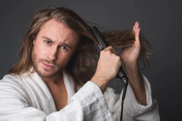 Stylish guy using hair straightener — Stock Photo, Image