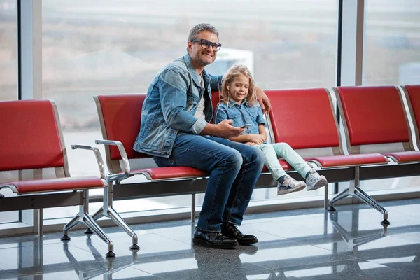 Gelukkig meisje en volwassen man rusten bij terminal lounge — Stockfoto