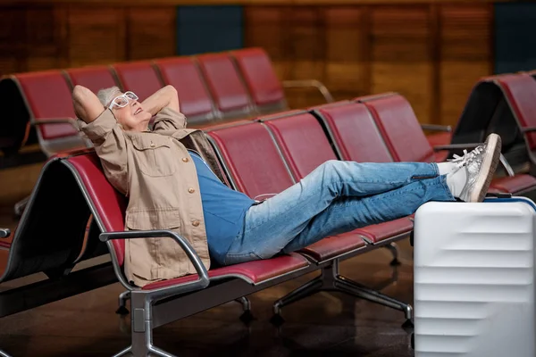 Boldog idős hölgy a padon, az utasforgalmi épület pihentető — Stock Fotó