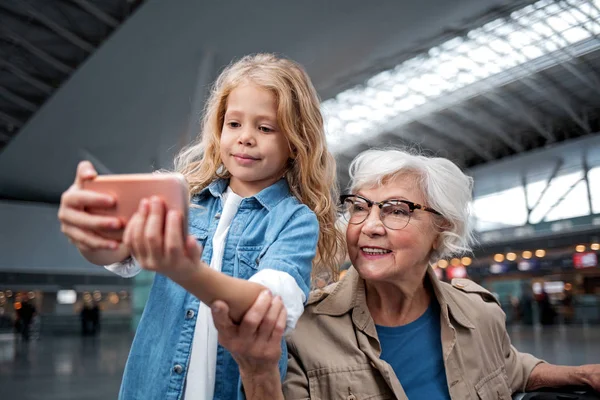 Оптимистичная внучка и ее бабушка фотографируются в терминале — стоковое фото