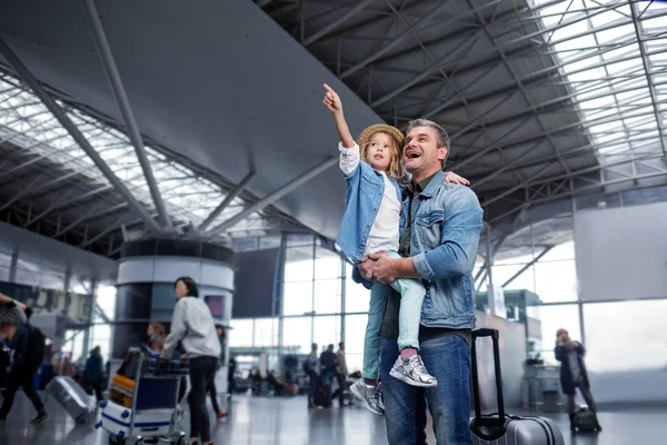 Здивований чоловік середнього віку стоїть з маленькою дівчинкою в терміналі — стокове фото