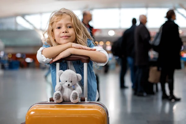 Optimistic cute little girl is standing at modern terminal