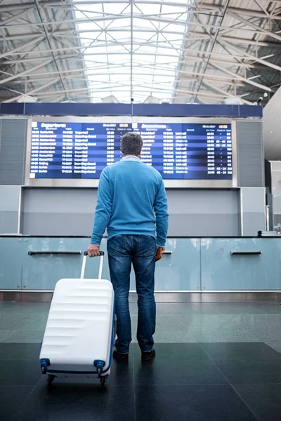 El hombre con equipaje está esperando el vuelo en la terminal moderna — Foto de Stock