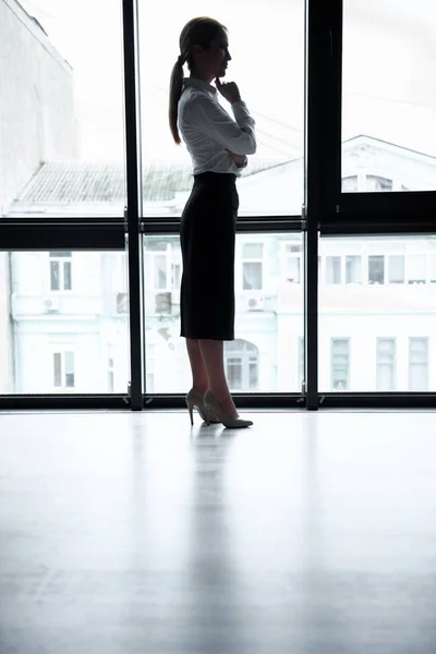 Nachdenkliche Geschäftsfrau steht am Fenster — Stockfoto