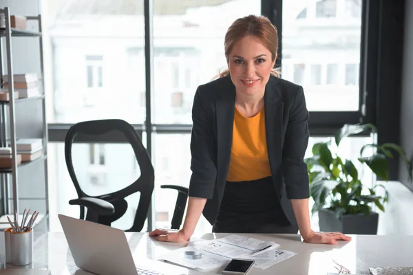 Alegre mujer de negocios apoyada en la mesa —  Fotos de Stock