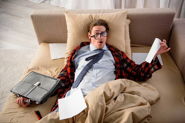 Уставший мужчина по уши в работе в спальне — стоковое фото