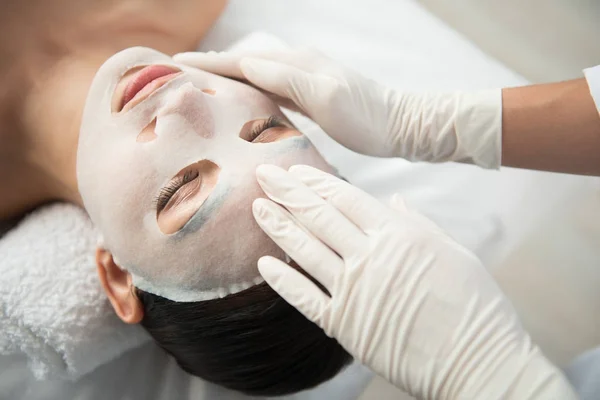 Esteticista aplicando produto cosmético hidratante na pele feminina — Fotografia de Stock